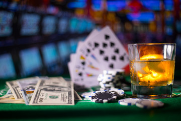 gambling, fortune, game and entertainment concept - close up of casino chips and whisky glass on table