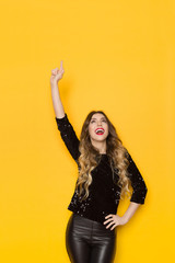 Young Woman In Black Sequin Sweater Is Pointing Up And Talking