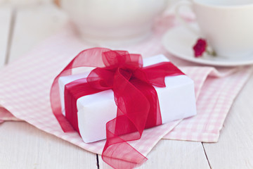 Composition with white gift box with red ribbon