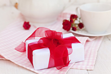 Composition with white gift box with red ribbon