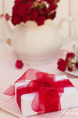 Fototapeta na wymiar Composition with white gift box with red ribbon