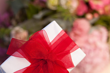 Composition with white gift box with red ribbon