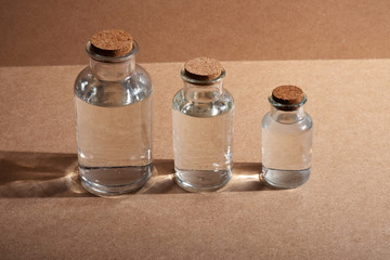 glass bottles with cork caps against a background of branded cardboard or wooden