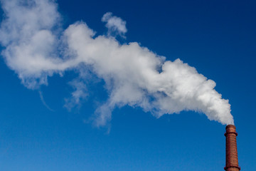 White smoke from the factory brick chimney. Blue sky. Ecology and production. Copy space.