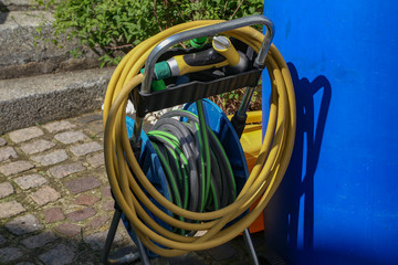 Watering hoses stand in the garden near the house