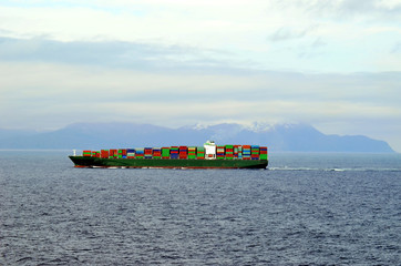 Big container ship, fully loaded with containers, sailing near Japanese island Hokkaido. 
