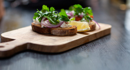 Delicious bruschetta with roasted tomatoes, goat cheese and herbs on wooden board. Organic food
