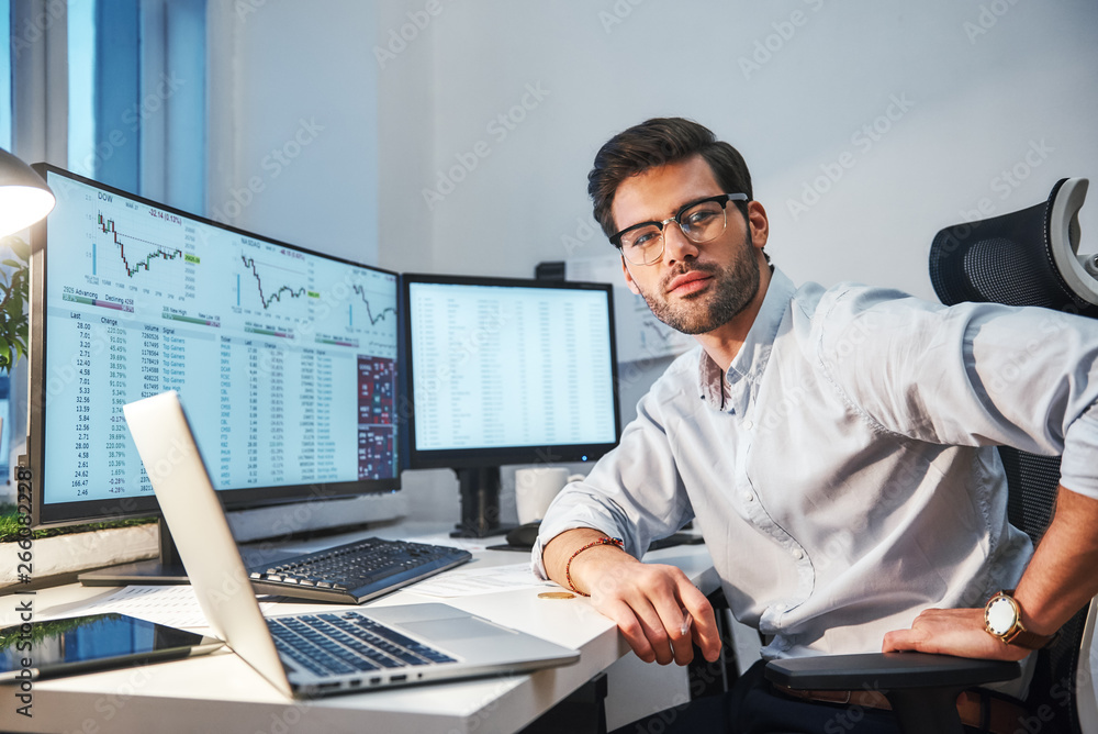 Poster confident and smart. young trader or businessman in eyewear and formal clothes is looking at camera 