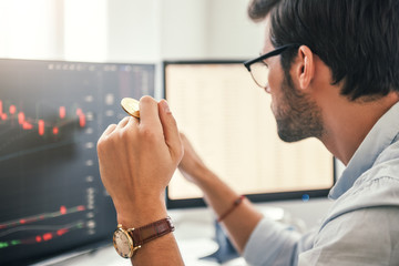 Investing. Close-up of young bearded trader in eyeglasses working with graph and financial reports...