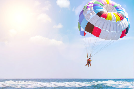 Parasailing water amusement - flying on a parachute behind a boat on a summer holiday by the sea in the resort. Space for text