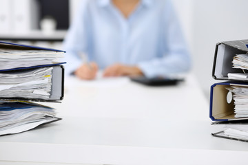 Binders with papers are waiting to be processed by business woman or bookkeeper back in blur....