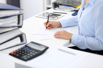 Unknown female bookkeeper or financial inspector calculating or checking balance, making report,...