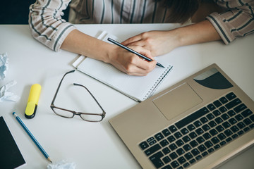 A young beautiful student girl does homework or writes a to-do list or this girl works in a home office. Home education or business or planning.