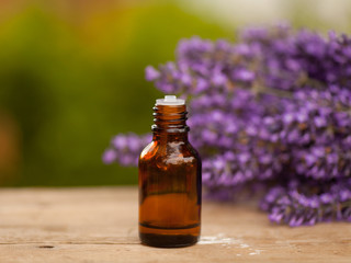Lavender oil container on wooden and greenery background with lavender 