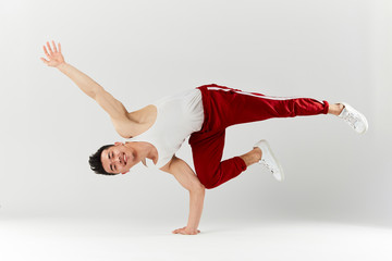 Stylish dressed in red sportswear asian personal break dancer trainer doing handstand on white background