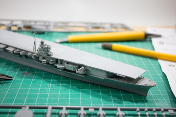 plastic model WW2 aircraft carrier with tools on cutting pad closeup.	