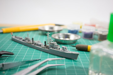 plastic model WW2 warship with tools on cutting pad closeup.	
