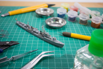 plastic model WW2 warship with tools on cutting pad closeup.	