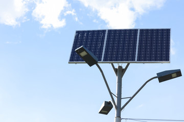 Obraz premium Solar cell lamp on sky background. Light support with lantern and installed solar panels on blue sky. Alternative energy from the sun