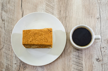 a piece of cake and a cup of coffee on a wooden table