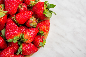 Garden fresh strawberries on wooden board on marble table