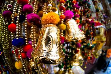 Fototapeta premium Dangling golden decorations with bells and puffs hanging in a store in chandni chowk delhi