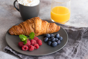 Continental breakfast, French croissant, coffee with milk, fruit and orange juice. Good morning concept.