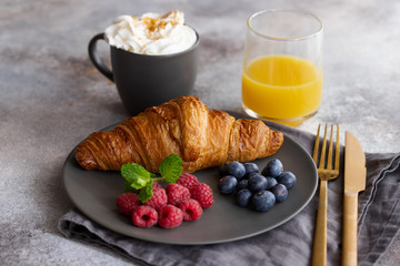 Continental breakfast, French croissant, coffee with milk, fruit and orange juice. Good morning concept.