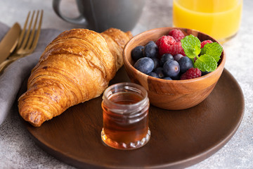 Fresh croissant, coffee with milk, fruit, syrup and orange juice. Continental breakfast background.