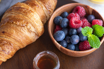 Fresh croissant, coffee with milk, fruit, syrup and orange juice. Continental breakfast background.