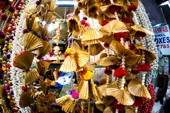 Dangling golden decorations with bells and puffs hanging in a store in chandni chowk delhi
