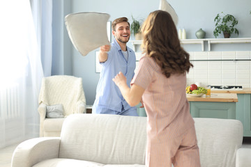 Happy loving couple having fun while having a pillow fight in the living room.