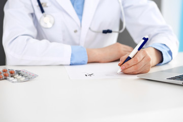 Female doctor filling up prescription form while sitting at the desk in hospital closeup.  Healthcare, insurance and excellent service in medicine concept 