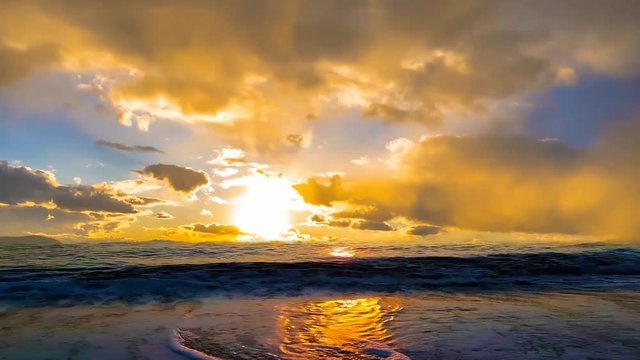 animated scene of waves on a beach with a beautiful time lapse sky of golden clouds in a sunset
