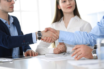 Business people shaking hands at meeting or negotiation, close-up. Group of unknown businessmen and women in modern office. Teamwork, partnership and handshake concept