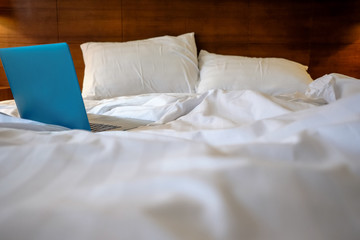 Fototapeta na wymiar Laptop on white bed. Work at home concept