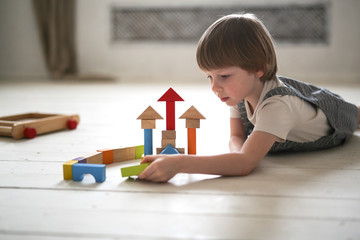 boy playing wooden constructor on floor at home