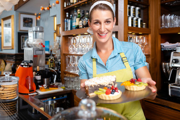 Smiling woman holding tarts and cake