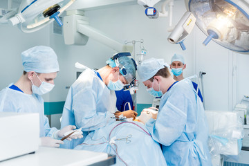 Spinal surgery. Group of surgeons in operating room with surgery equipment. Laminectomy