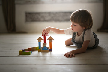 boy playing wooden constructor on floor at home