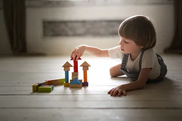 Fototapete Lego boy playing wooden constructor on floor at home  © natalialeb