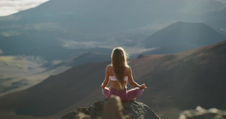 Young peaceful woman meditating on the top of a mountain, zen yoga meditation practice in nature