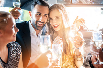 Couple celebrating party in limousine with friends