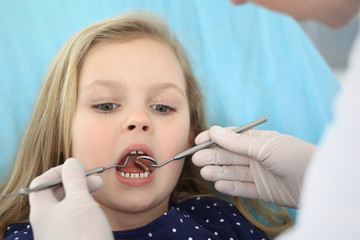 Little baby girl sitting at dental chair with open mouth during oral check up while doctor. Visiting dentist office. Medicine concept