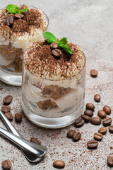 two portions Classic tiramisu dessert in a glass on concrete background