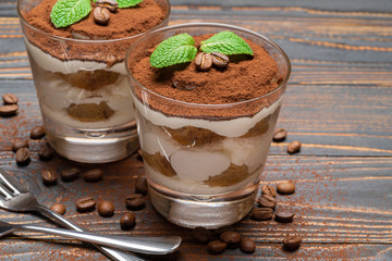 two portions Classic tiramisu dessert in a glass on wooden background