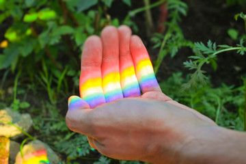 rainbow color from a prism on a sunny day in a man's hand, the theme of social equality and freedom...