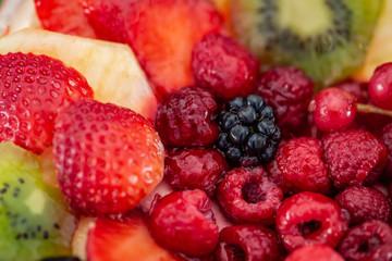 Fruits and berries in sweet gelatin on the cake. Background of strawberries, kiwi, currants, raspberry, pineapple, blackberry. Delicious dessert. Soft focus. Closeup. Top view.