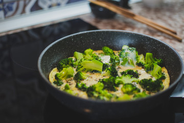 cooking broccoli with eggs in a frying pan
