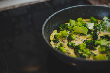 cooking broccoli with eggs in a frying pan